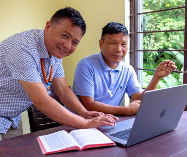 kaksi miestä tietokoneen ja Raamatun kanssa